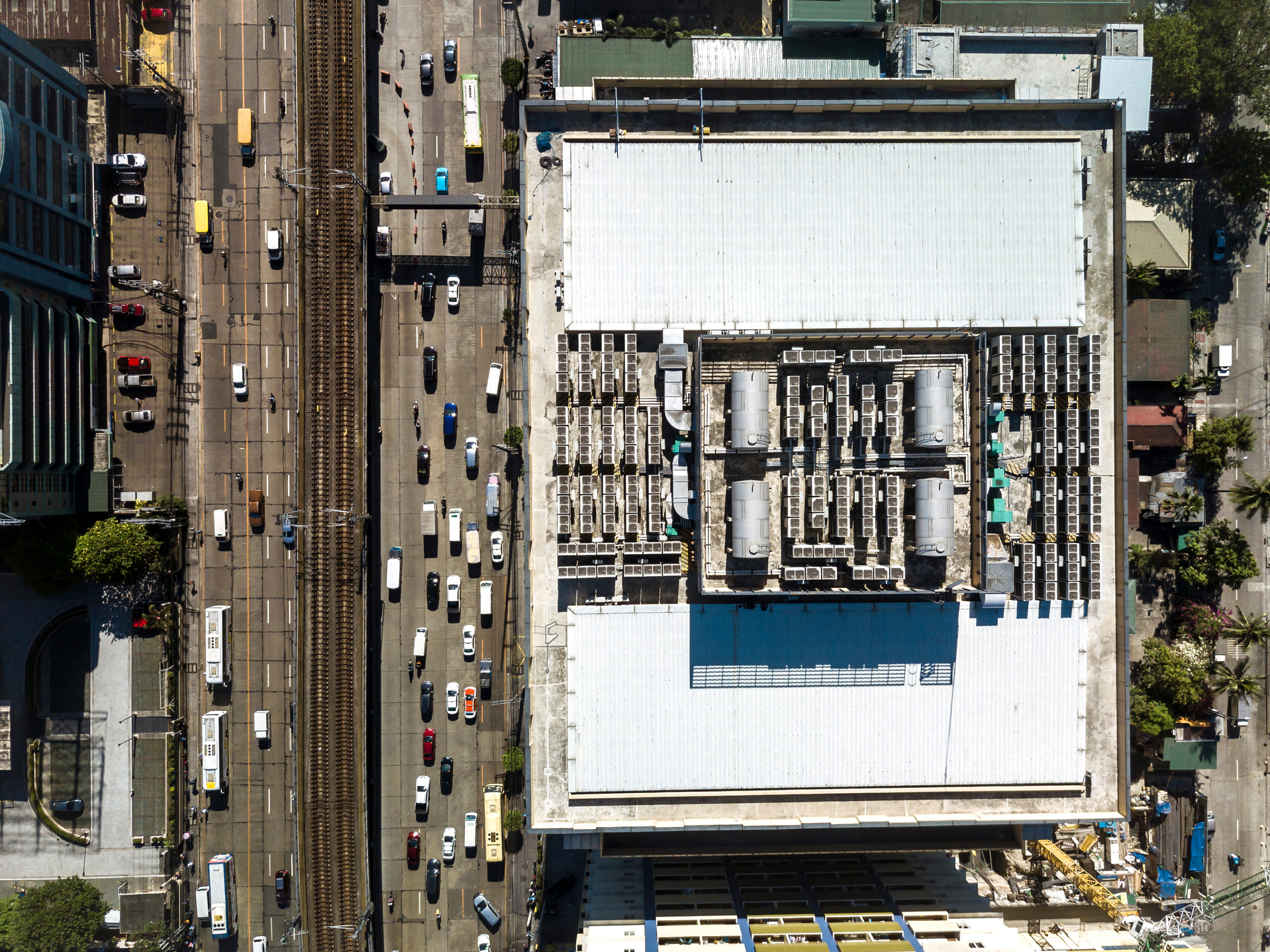 Top view of the roof deck of an office building, with installed VRF HVACs and water storage tanks. A large avenue with a rail system installed in the center lane.